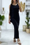 Long black dress with flounce on one sleeve and golden accessory on the collar.