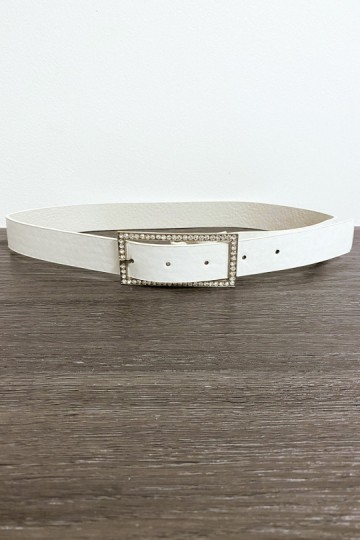 Cinturón de piel sintética blanca con hebilla rectangular adornada con pedrería.